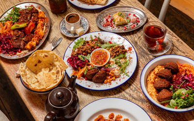 over head shot of the wooden table at lavash laid our with various middle eastern dishes