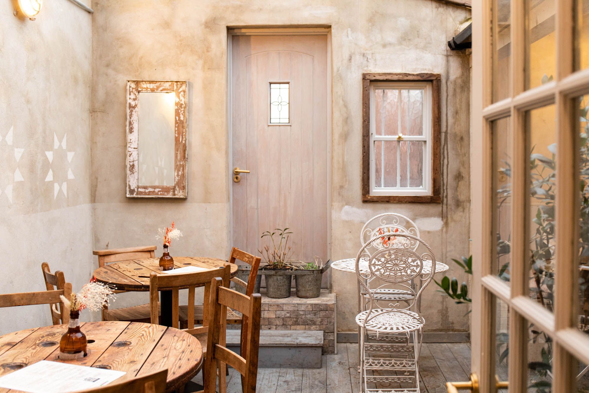 rustic looking dining area at the Lavash Brighton with two wooden tables and chairs as well as one white table and white chair