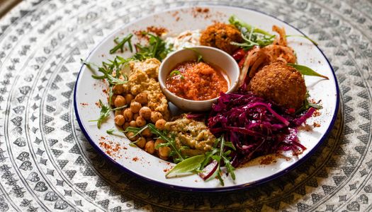 colorful looking plate with purple cabbage, some chickpeas, falafel and orange sauce served in white plate at Lavash Brighton