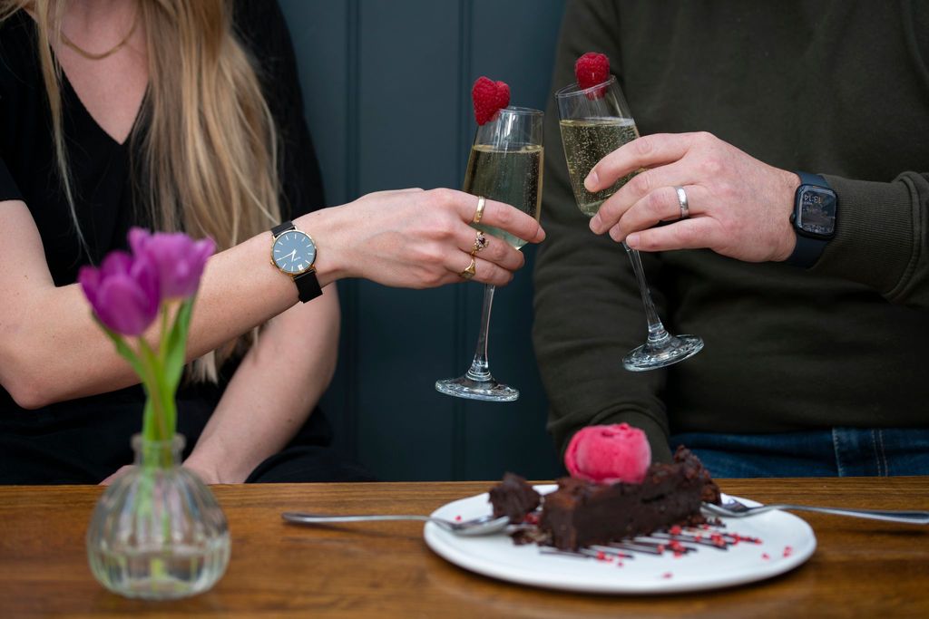 Valentines Day date two people having a toast with glass of Posecco and enjoying brownie, Brighton Food guide for the February