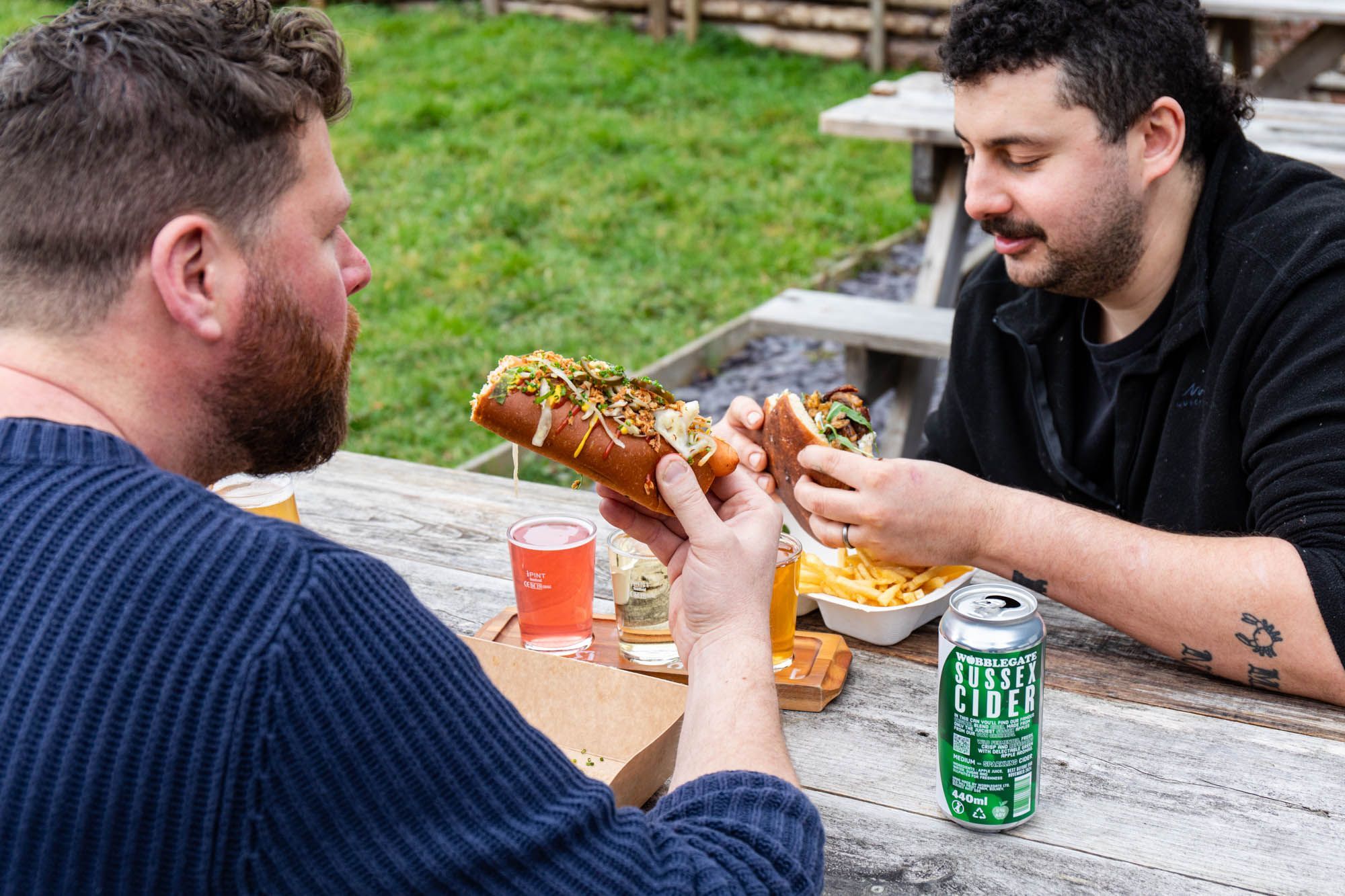 two men enjoying their sandwiches and beer in the garden of The Cider Tap Sussex