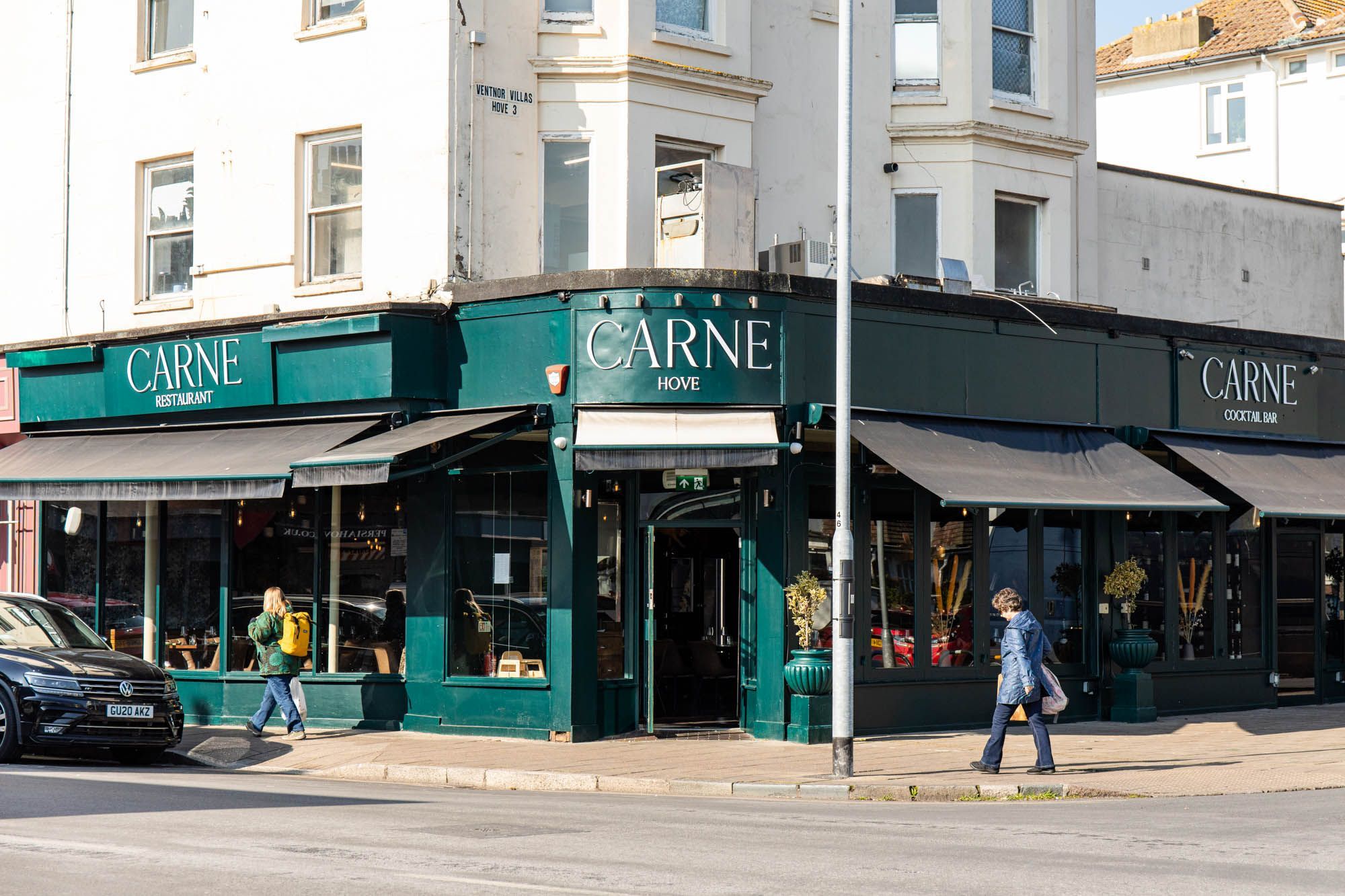 exterior shot of the Carne Hove from the far, green wall and Carne written with white letters