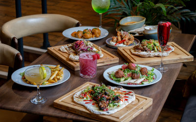 Middle Eastern food at Occulist served on a wooden table with cocktails.
