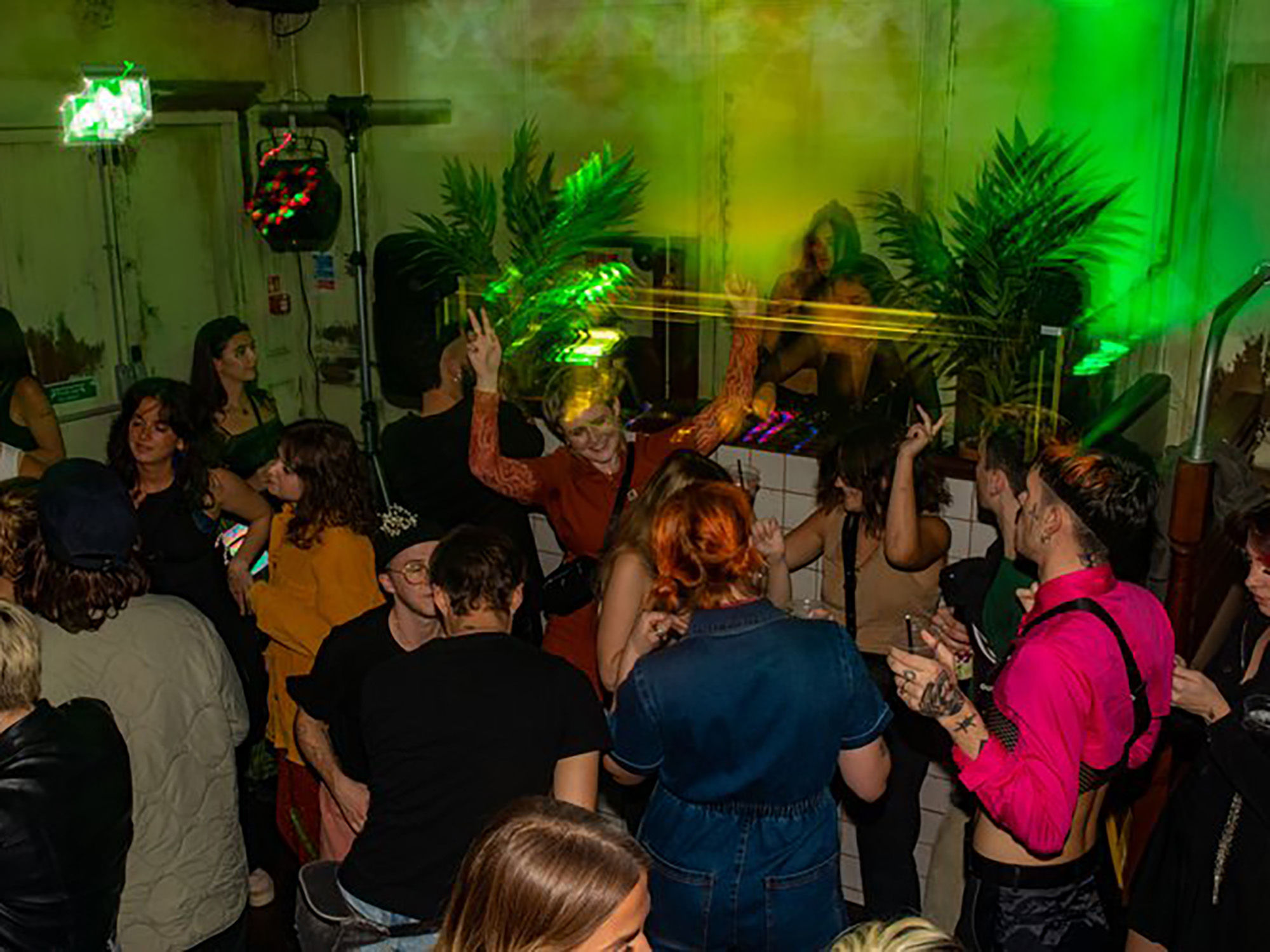 People dancing with a green light and disco ball.