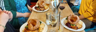 Group of six friends celebrating birthday at Arcobalno Brighton, they are being served Sunday roast with variety of drinks