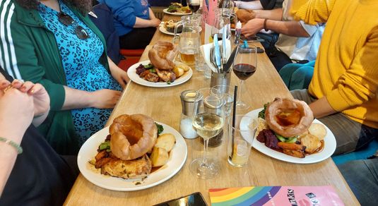 Group of six friends celebrating birthday at Arcobalno Brighton, they are being served Sunday roast with variety of drinks