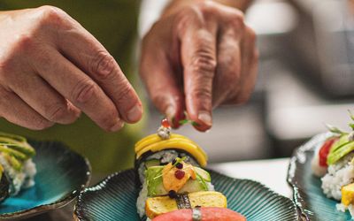 chef adding sushi on plate.