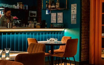 interior shot of the brighton cocktail company, brown chairs and tables and light blue walls