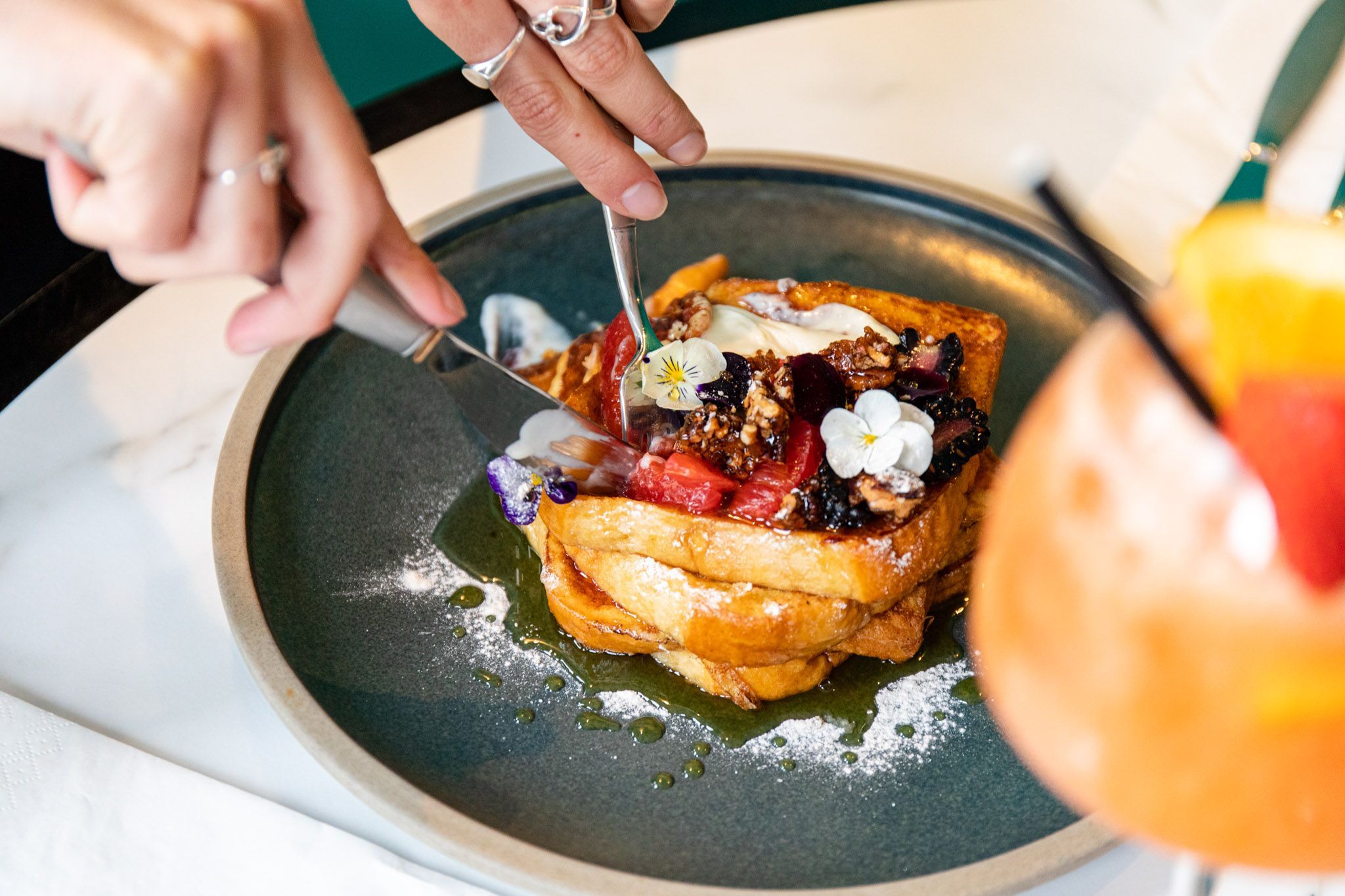 mouthwatering French toast being cut with knife and served with cocktail at the brunch 