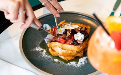 mouthwatering French toast being cut with knife and served with cocktail at the brunch