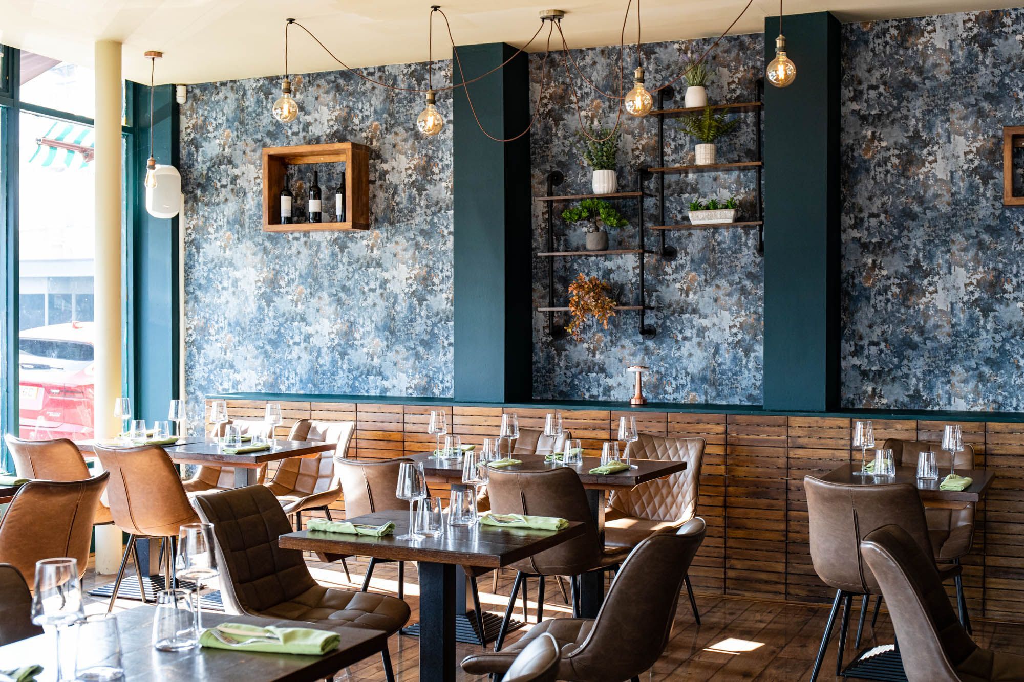 beautiful interior at the new restaurant Carne Hove, brown tables and chairs, dark green walls with wine shelves