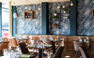 beautiful interior at the new restaurant Carne Hove, brown tables and chairs, dark green walls with wine shelves