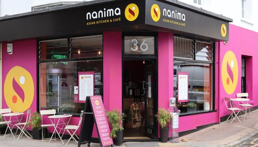 exterior shot of the Nanima Brighton, pink and black walls and chairs and tables as a part of outdoor seating