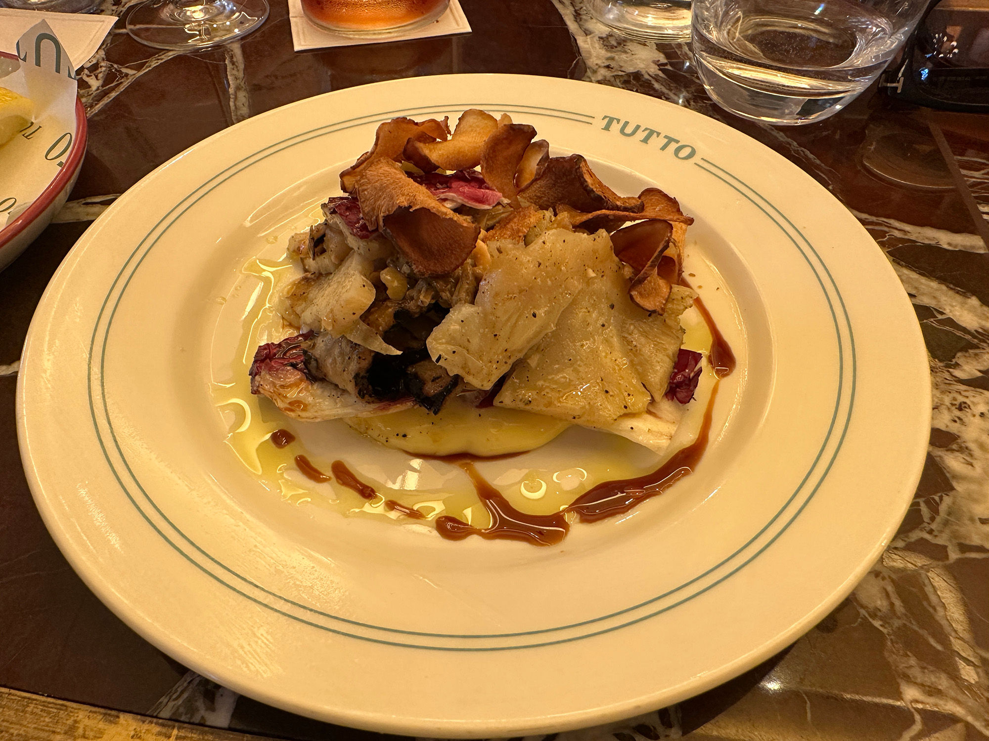 Celeriac and mushroom dish with a drizzle of oil served on a Tutto branded plate from the Italian sharing menu.