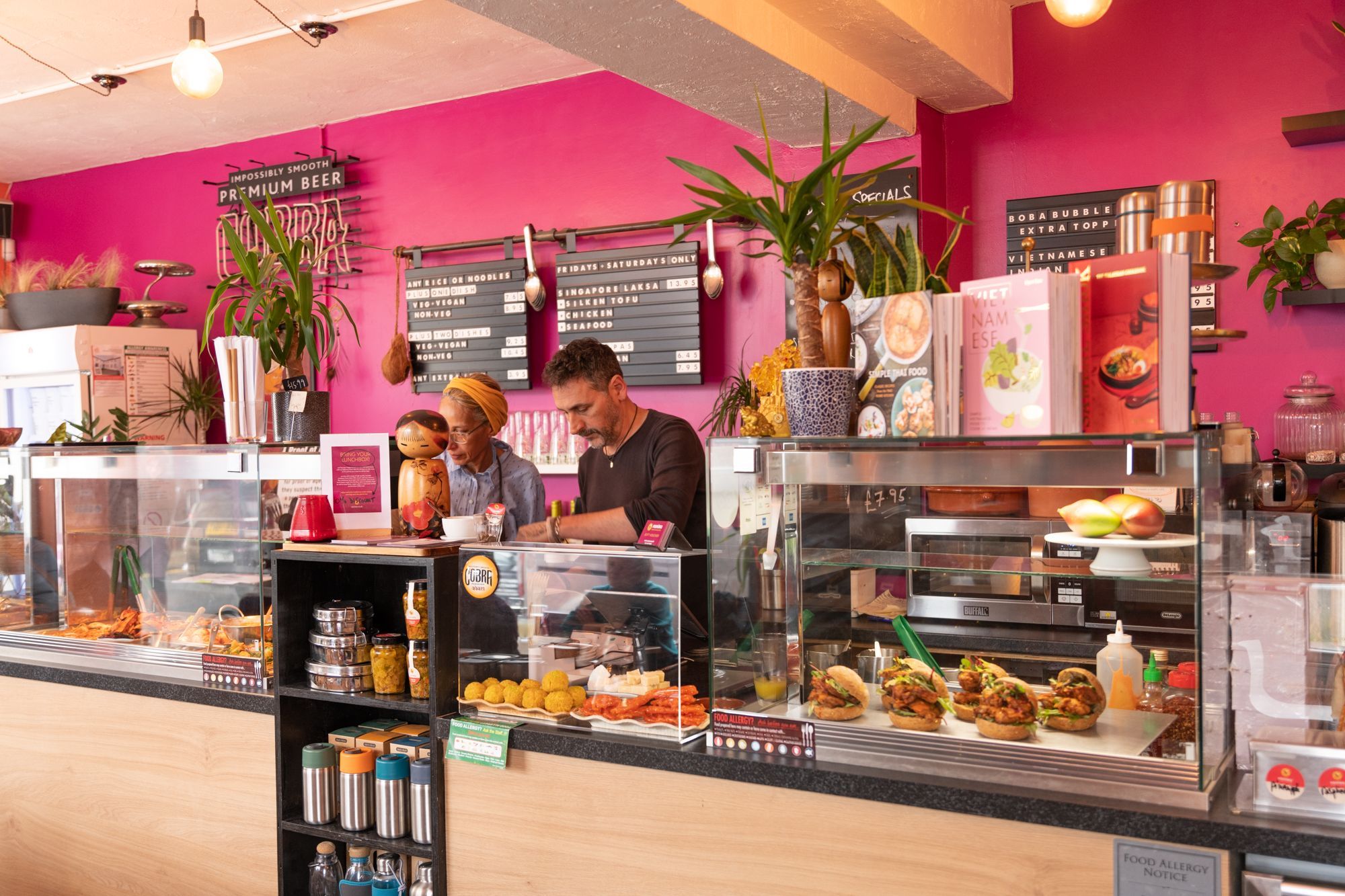  a man and a woman, owners of the venue behind the desk preparing food to be served