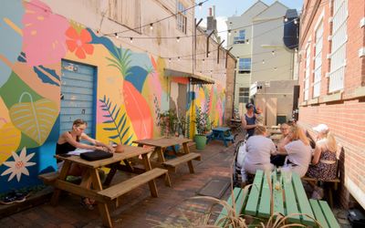 colorful walls in the Post House garden in Brighton, people sitting by on the benches and enjoying their food and drinks
