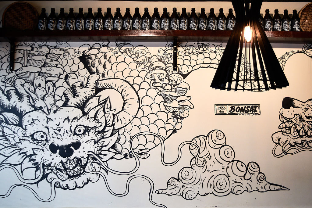 Dragon artwork on the wall at Bonsai Plant Kitchen with a shelf of bottle beer. Located on Baker Street in Brighton. Featured in our veganuary guide