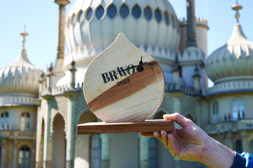 The BRAVO 2023 trophy held up and photographed in front of the Brighton Pavilion on a sunny day.