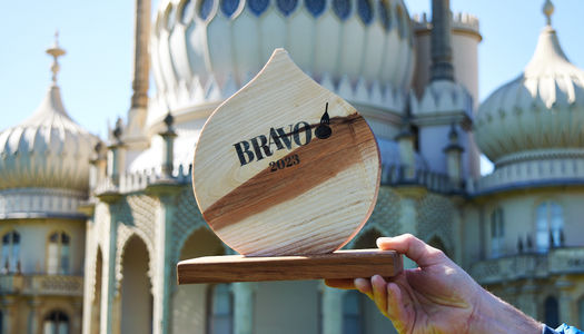 The BRAVO 2023 trophy held up and photographed in front of the Brighton Pavilion on a sunny day.