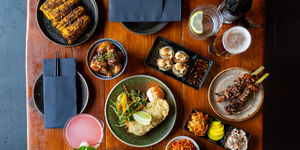 over head shot if the brown table at Bonsai Plant Kitchen laid out with vegan small plates and cocktails. Vegan restaurant located on Baker Street off London Road in Brighton.