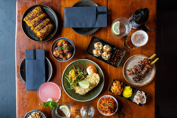 over head shot if the brown table at Bonsai Plant Kitchen laid out with vegan small plates and cocktails. Vegan restaurant located on Baker Street off London Road in Brighton.