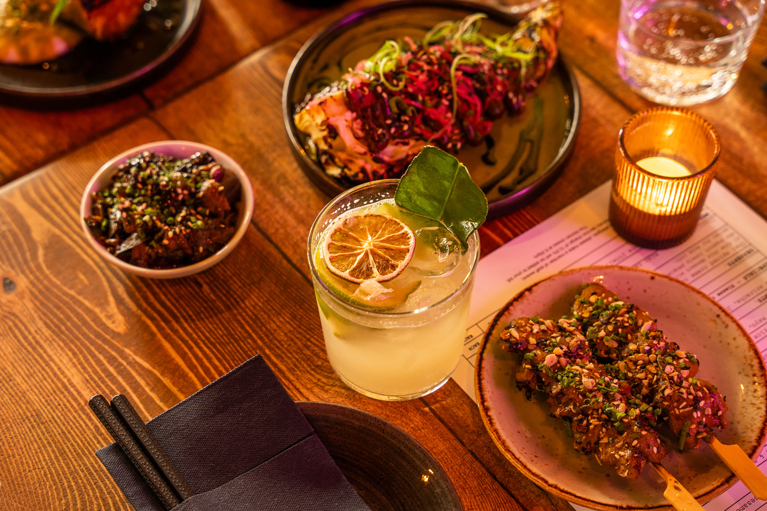 close up shot of two dishes, side and cocktails served on the wooden table at Bonsai Plant Kitchen