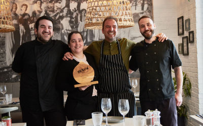 A team photo of the staff at Nostos inside the restaurant with the BRAVO trophy.
