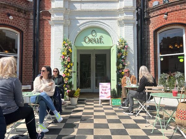 An Ouef brunch visit. The entrance of the Hove cafe with outside seating a people sitting outside at tables.