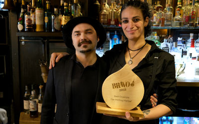 Two people standing behind a cocktail bar dressed in black holding a wooden trophy. Bars in brighton. Brighton Clubs