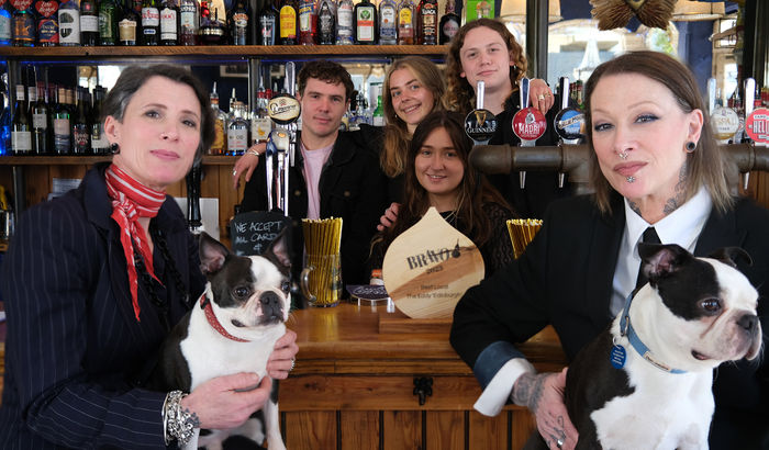 The team at The Eddy with their dogs in by the bar with the BRAVO wooden trophy.