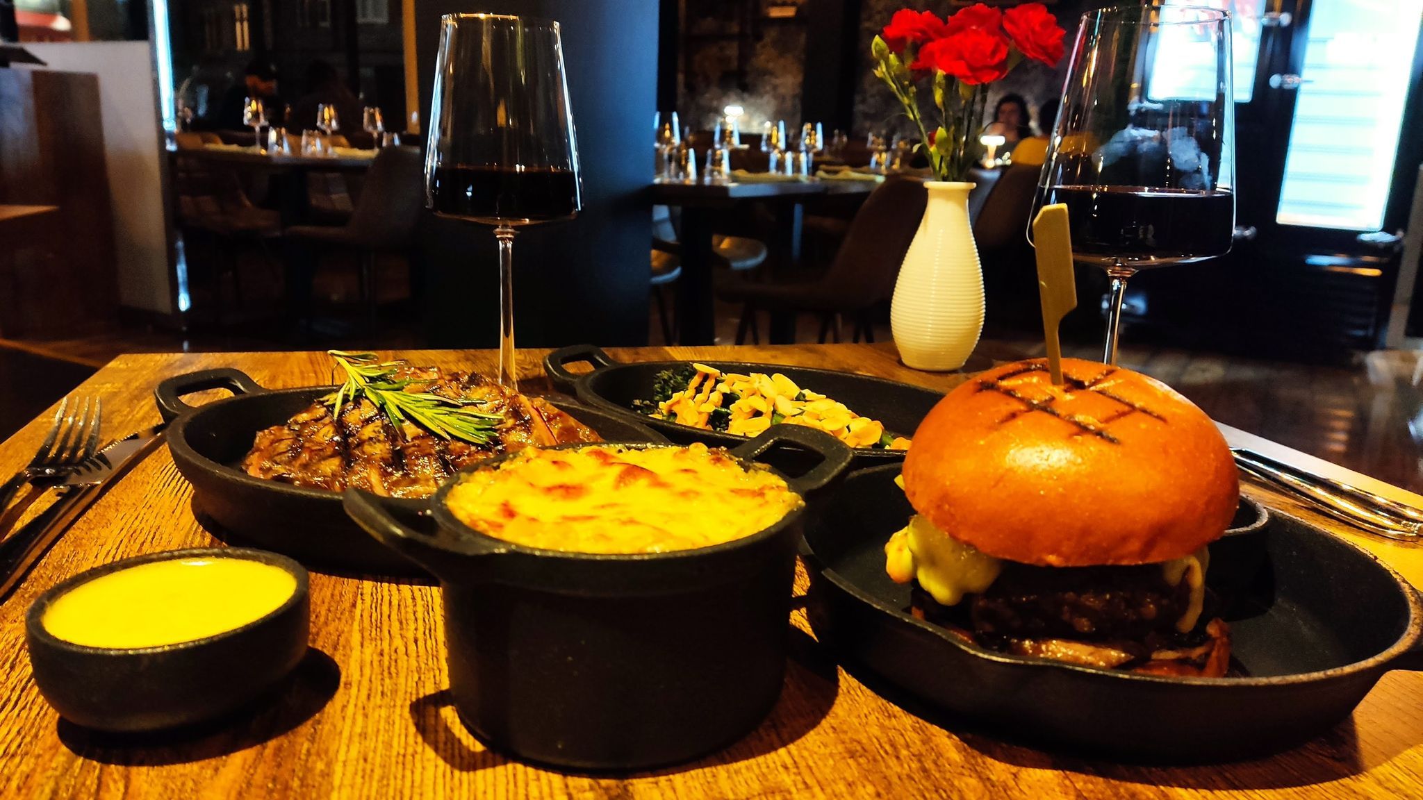 brown table laid out with burger, steak, gravy, hot pot of ox cheek mac and cheese