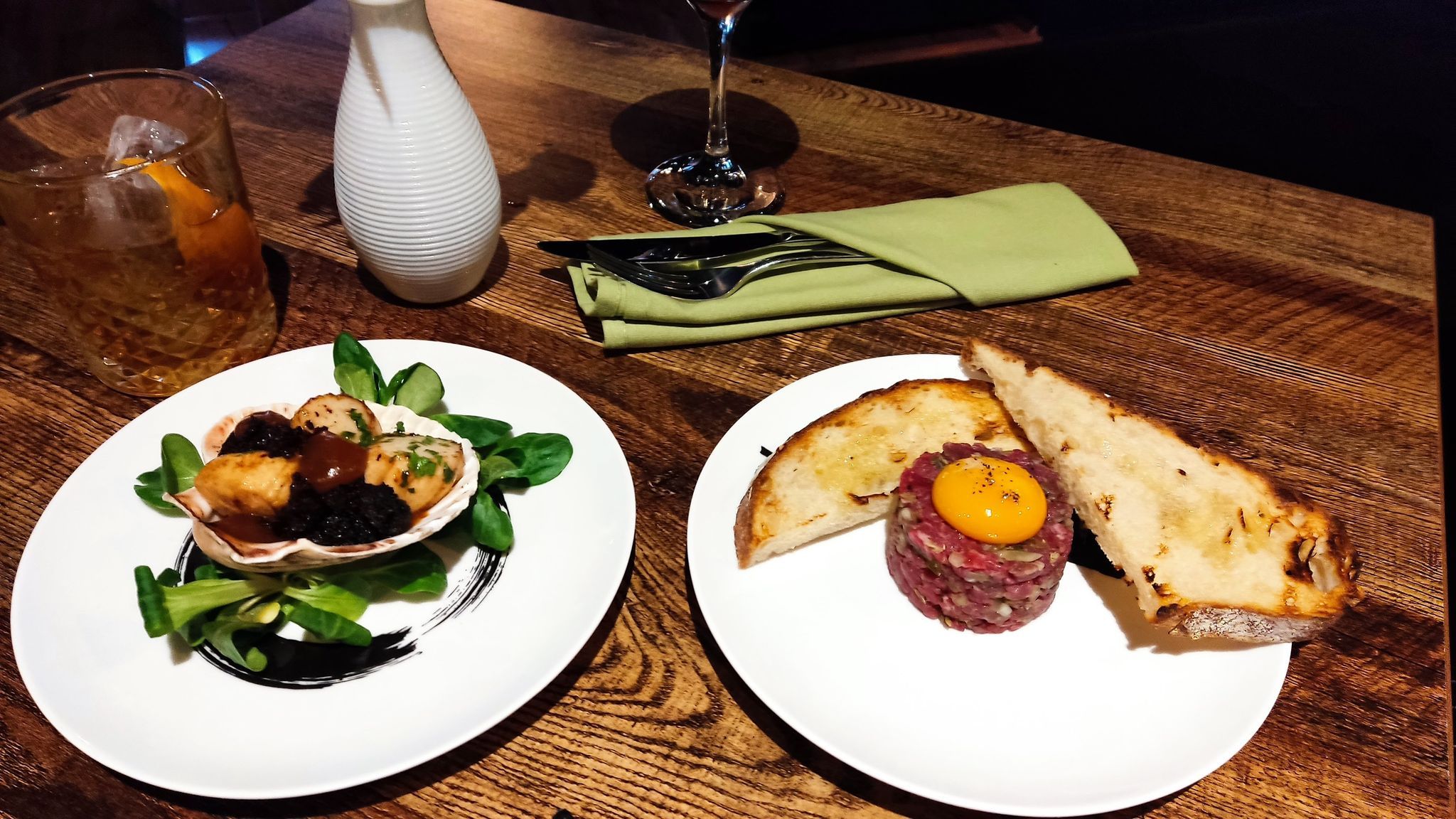 egg tartare and bread on the white plate and scallop, burnt apple, and black pudding dish dish served on another plate at the Carne, new restaurant in Hove