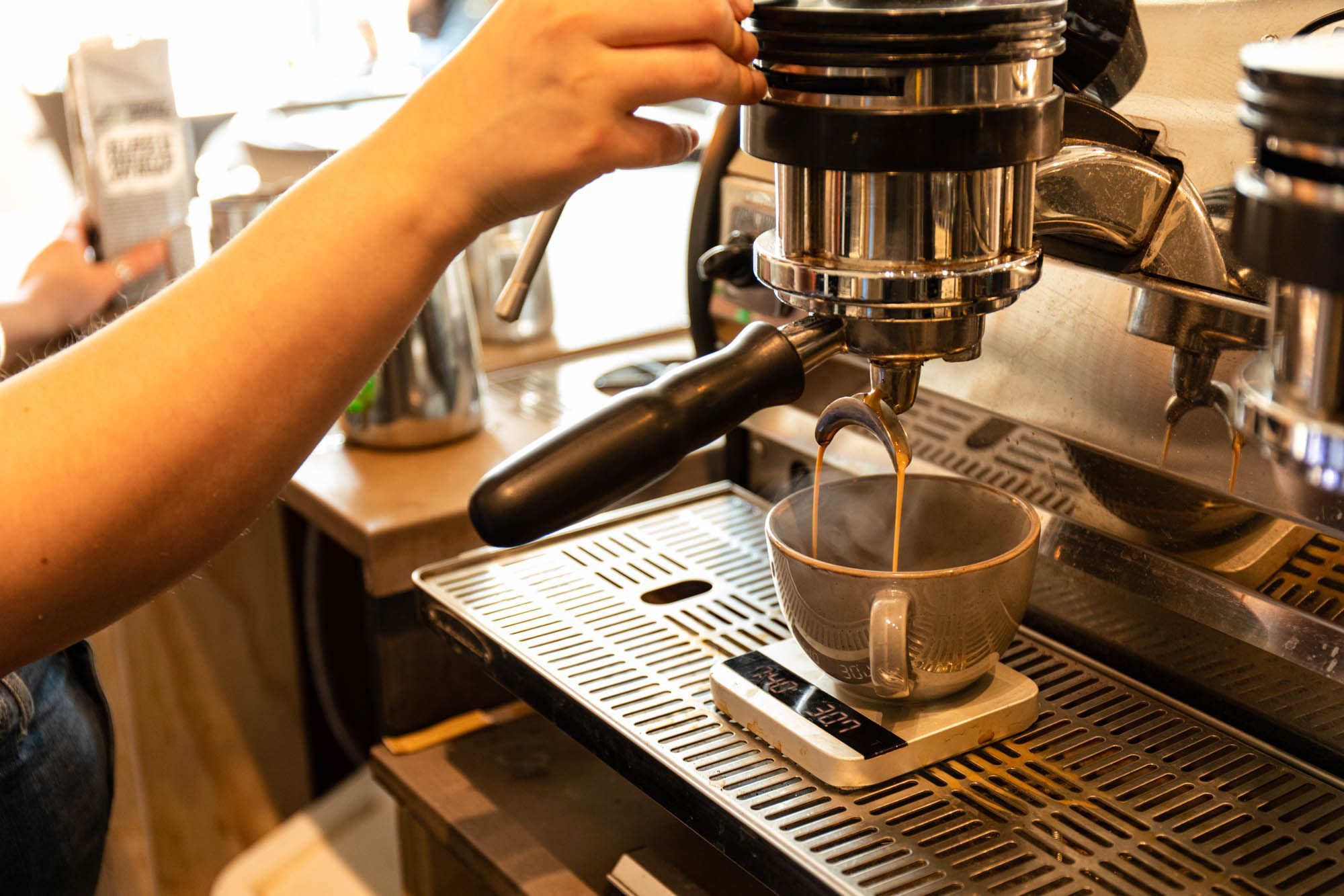 grey cup being filled with coffee from the coffee machine at the White Cloud Coffee