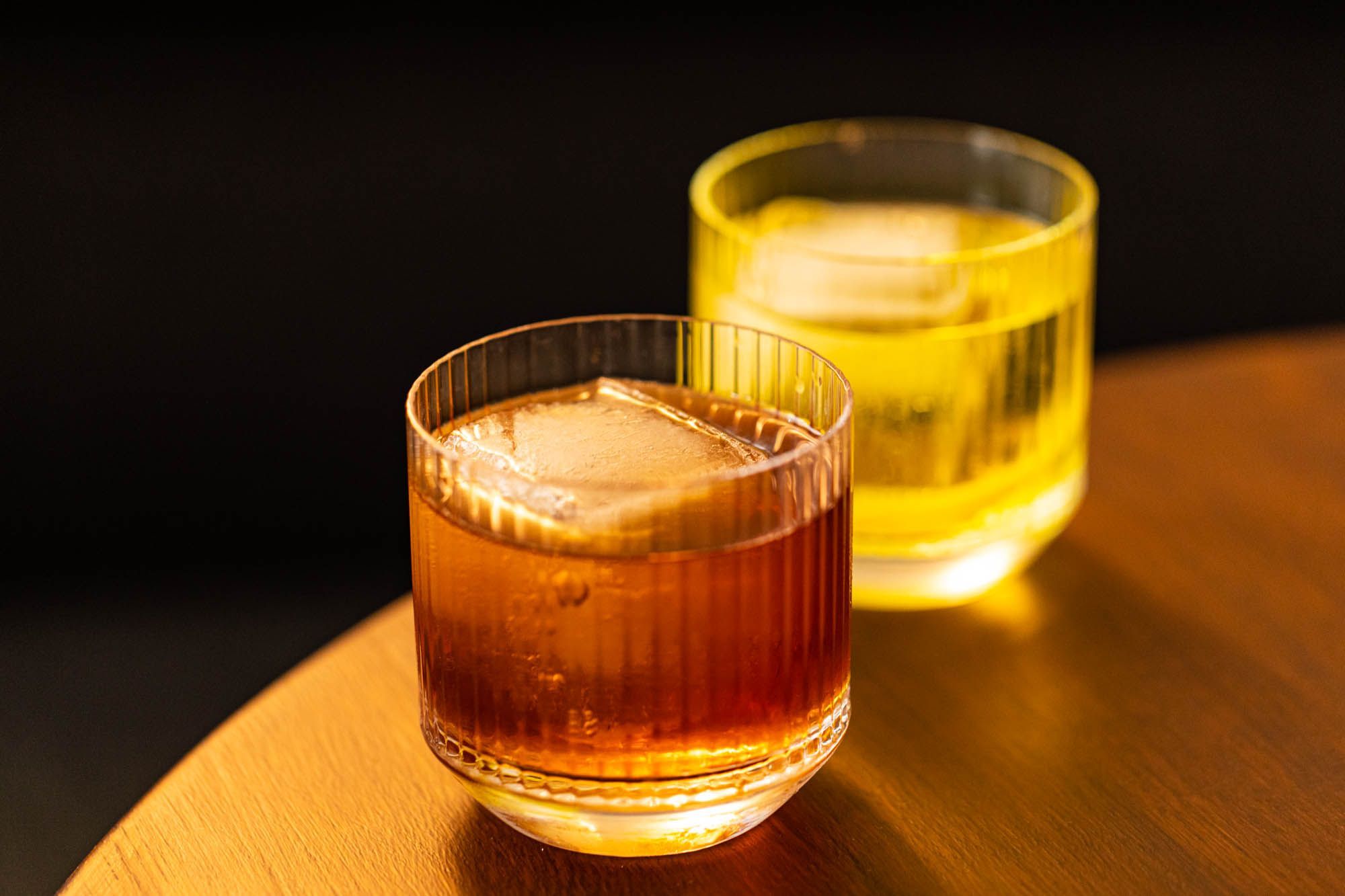 two different cocktails in small cups served at the brown table