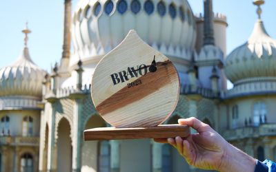 The BRAVO 2023 trophy held up in front of the Brighton Pavilion on a sunny day.