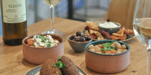 Small plates of meze with a glass of white wine served on a wooden table. At Vios cafe in Brighton. Part of our round up of places to Eat in Brighton
