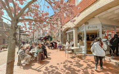 exterior shot of the Vios Brighton cafe and their outdoor seating with people.