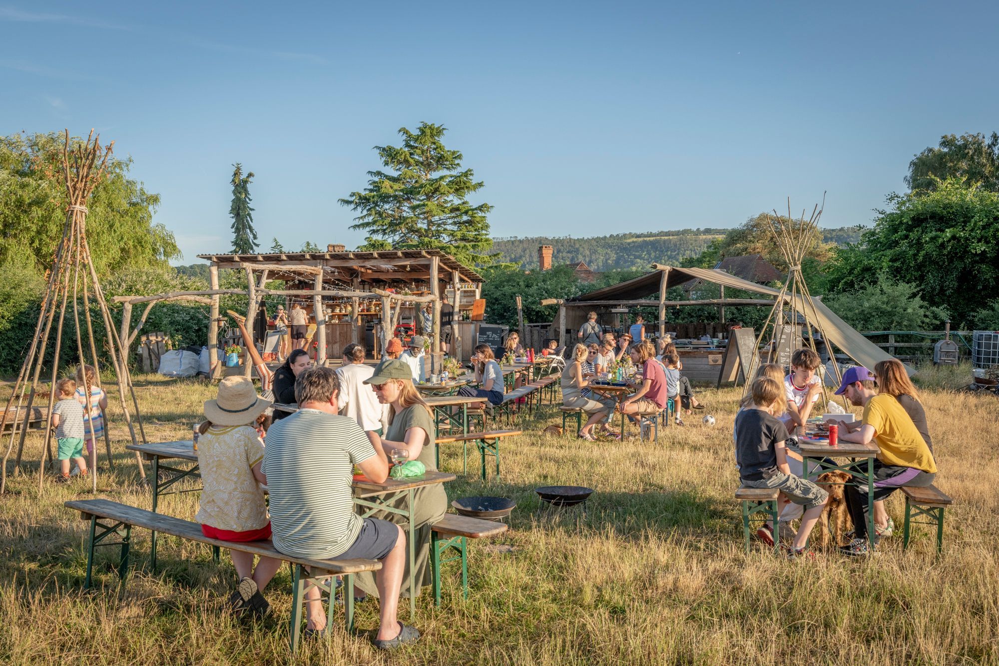 people sitting on the wooden tables and benches at the Woodfire Camp site