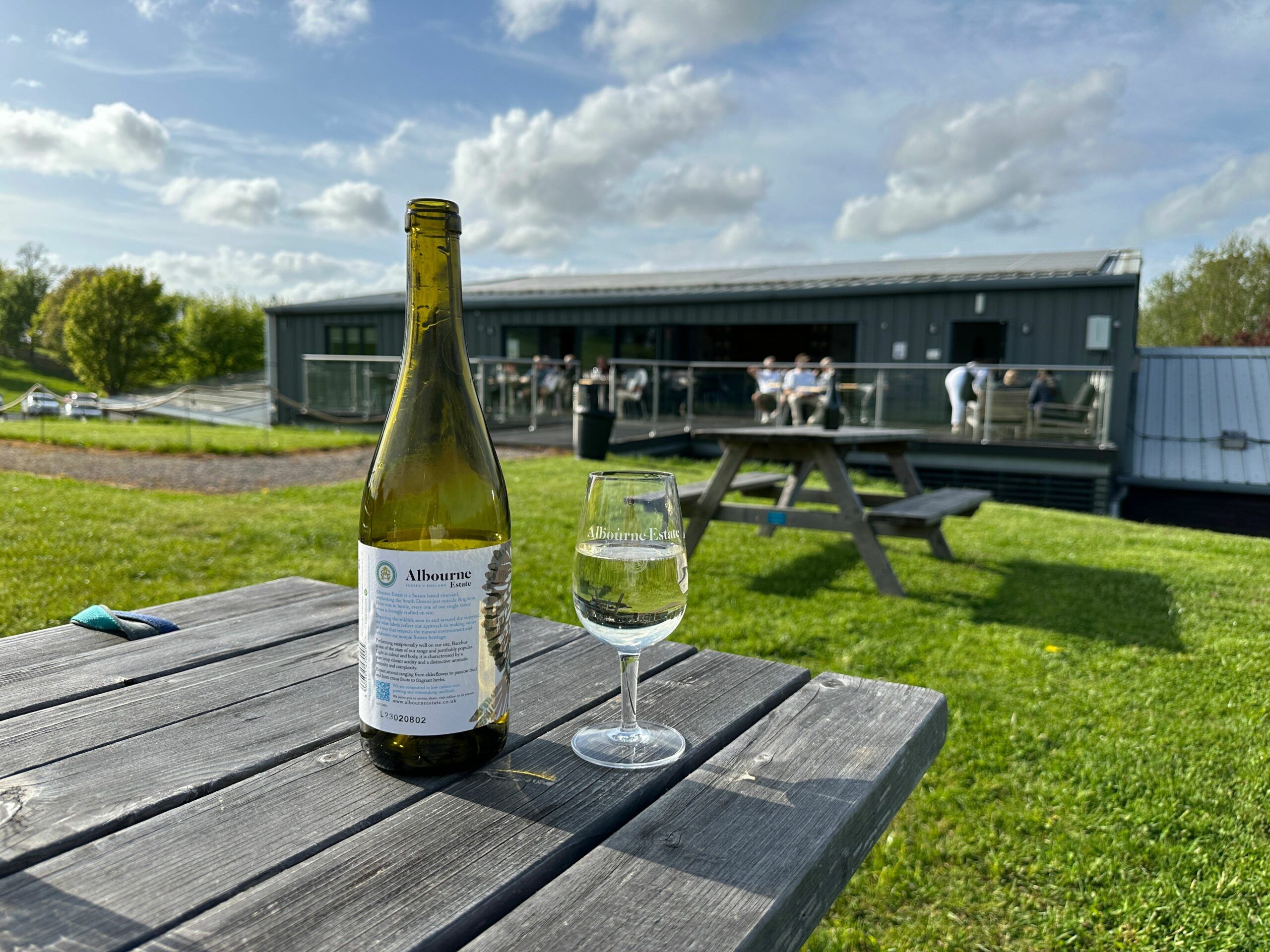 bottle of wine on the wooden table in the garden of Albourne Wine Estate. Supper Club