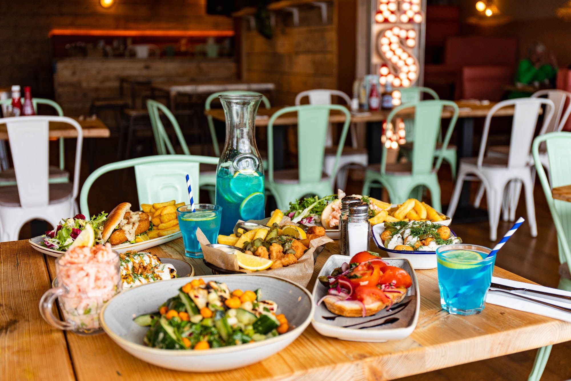 table laid out with lots of seafood dishes and blue lagoon cocktail