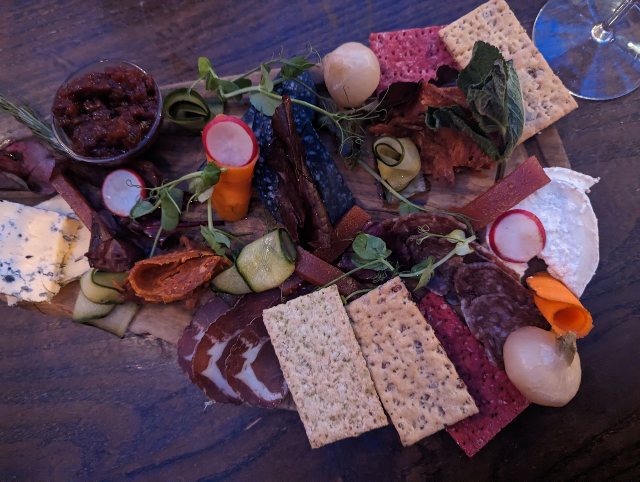 delicious looking charcuterie board with crackers, dry aged meat, chutney, bits of vegetables and cheese. spring menu