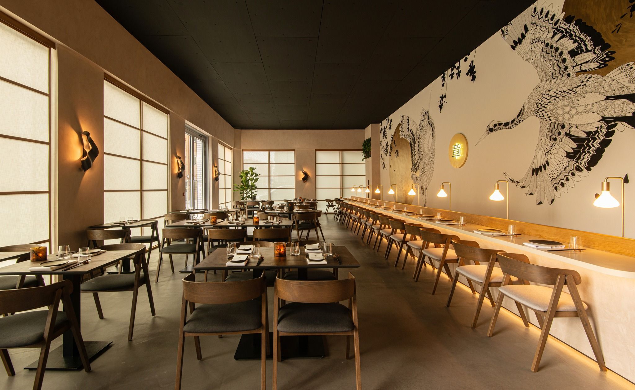 interior shot of the fumi, Japanese restaurant in Brighton. Wooden brown tables and chairs, dim lights and art on the wall