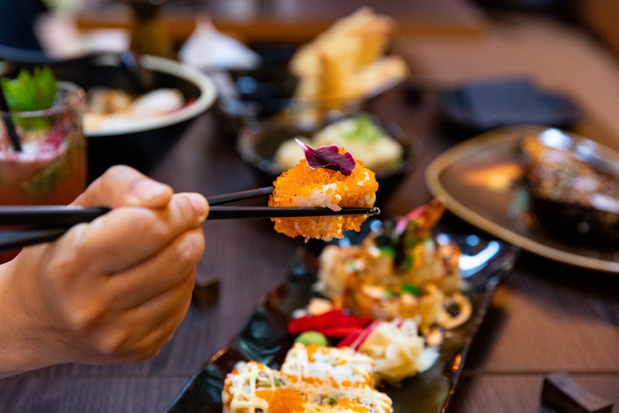hands using chopstick to hold fried sushi at Wabi Sabi