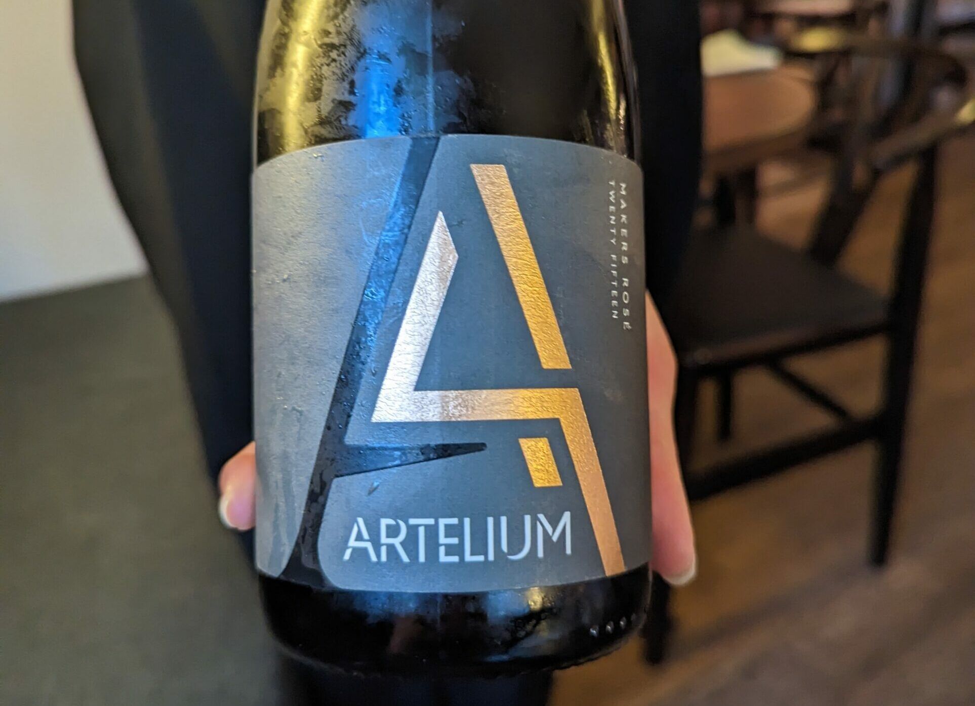 Person holding bottle of Atelium wine. A Voyage of Discovery: Hidden Treasure at Dilsk
