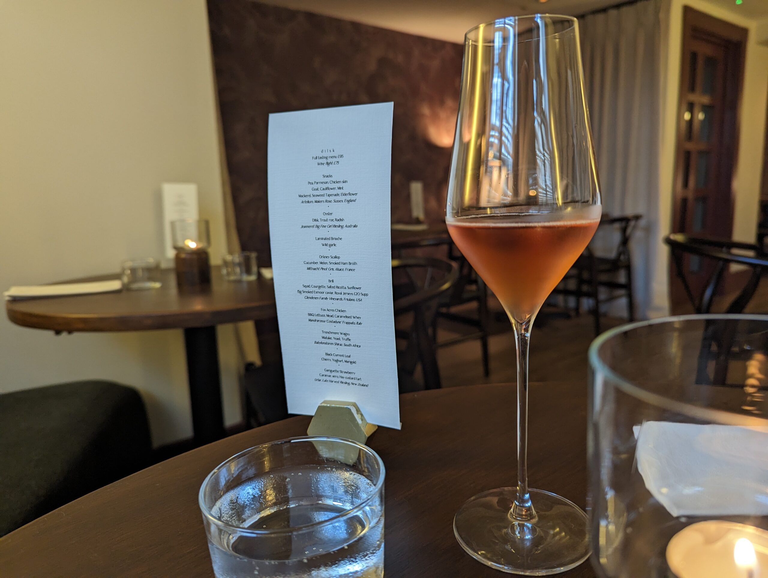 A Voyage of Discovery: Hidden Treasure at Dilsk. Glas of wine and menu on the table