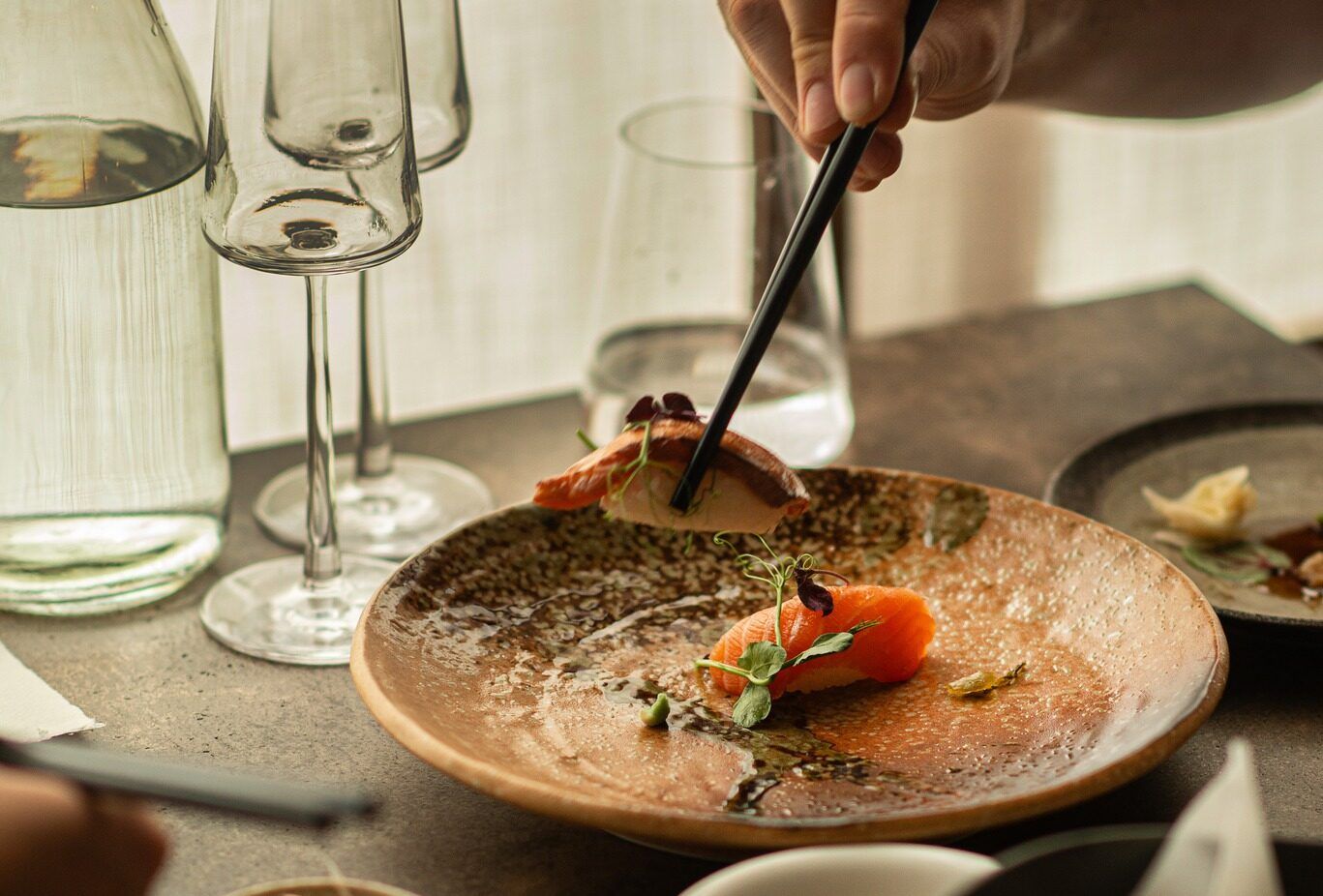 person holding dumpling with a sticks at Fumi