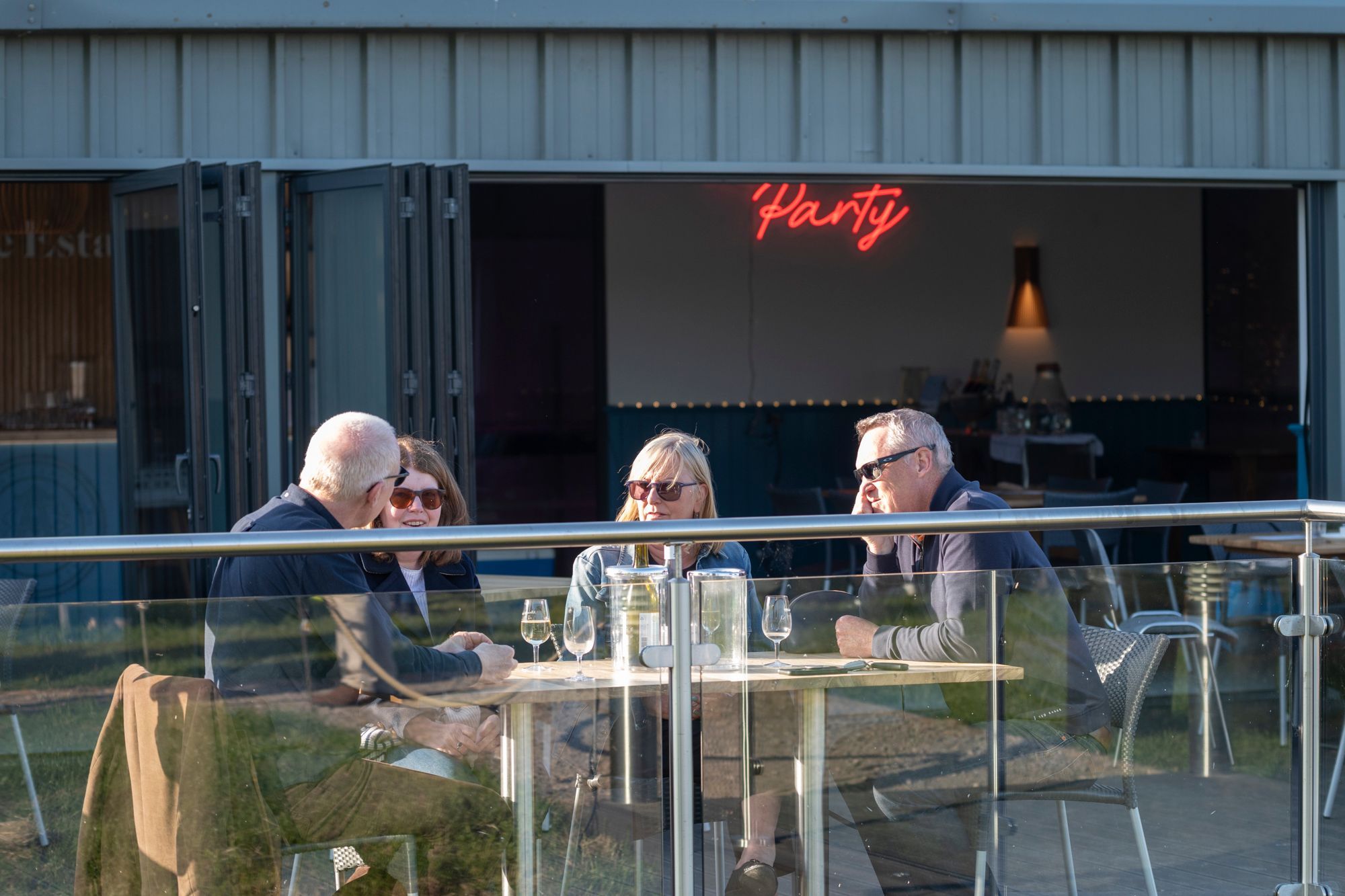 three people sitting on the Albourne Estate terrace enjoying their wine