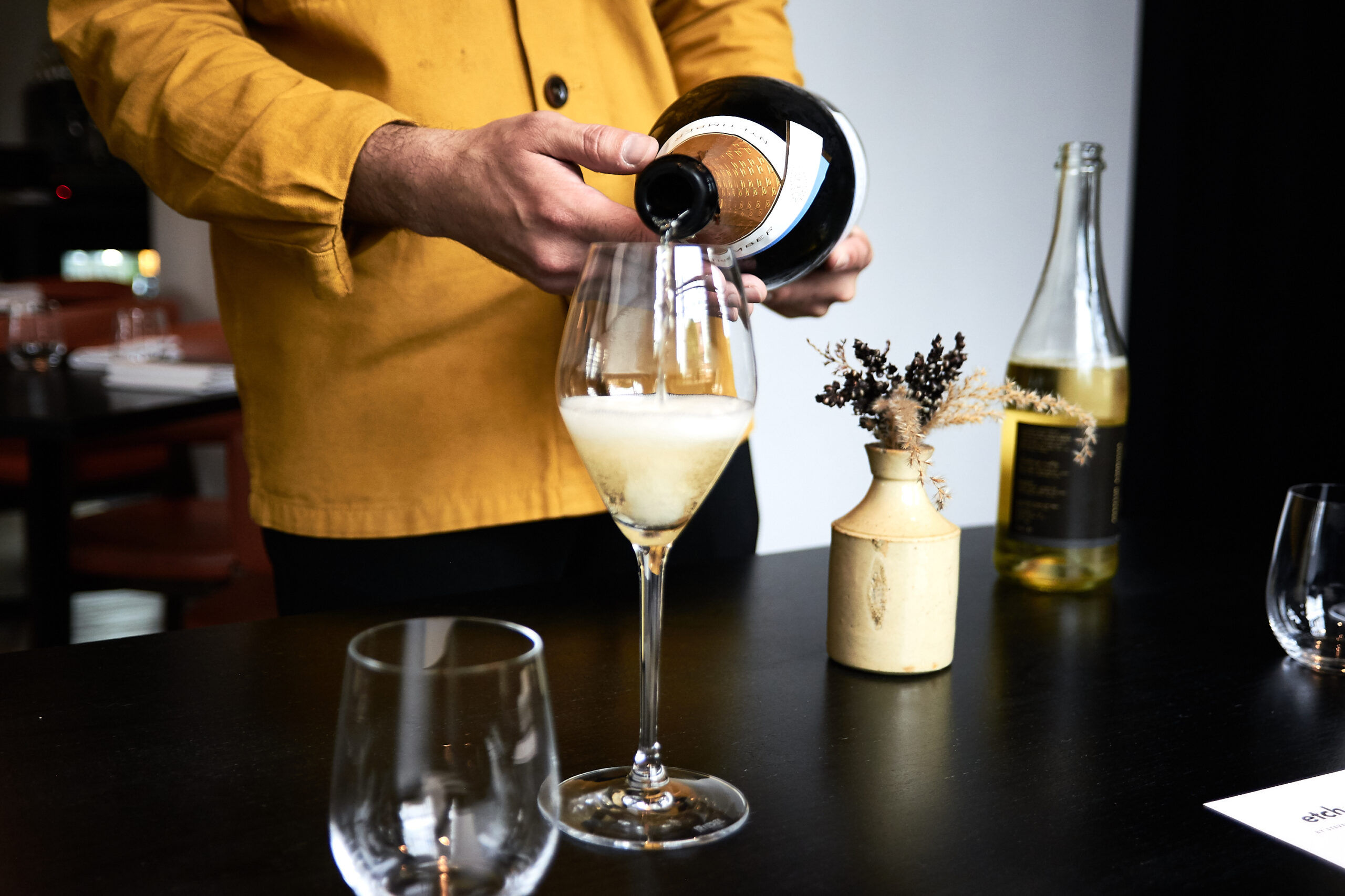 Wine being poured at etch. restaurant by a man in a yellow shirt for the four-course lunch.