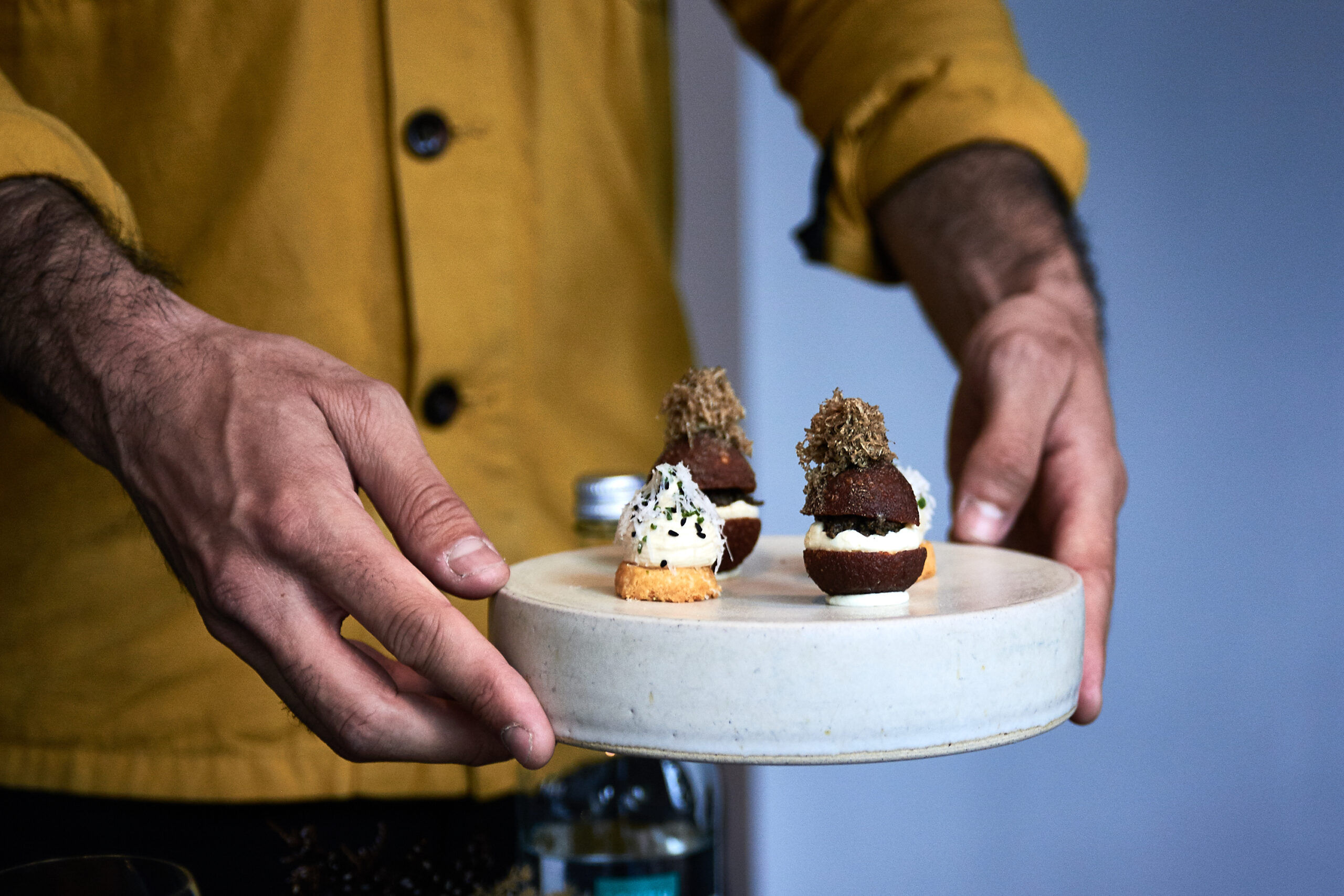 Snacks being served by a man in a yellow shirt at etch. restaurant for the four-course lunch