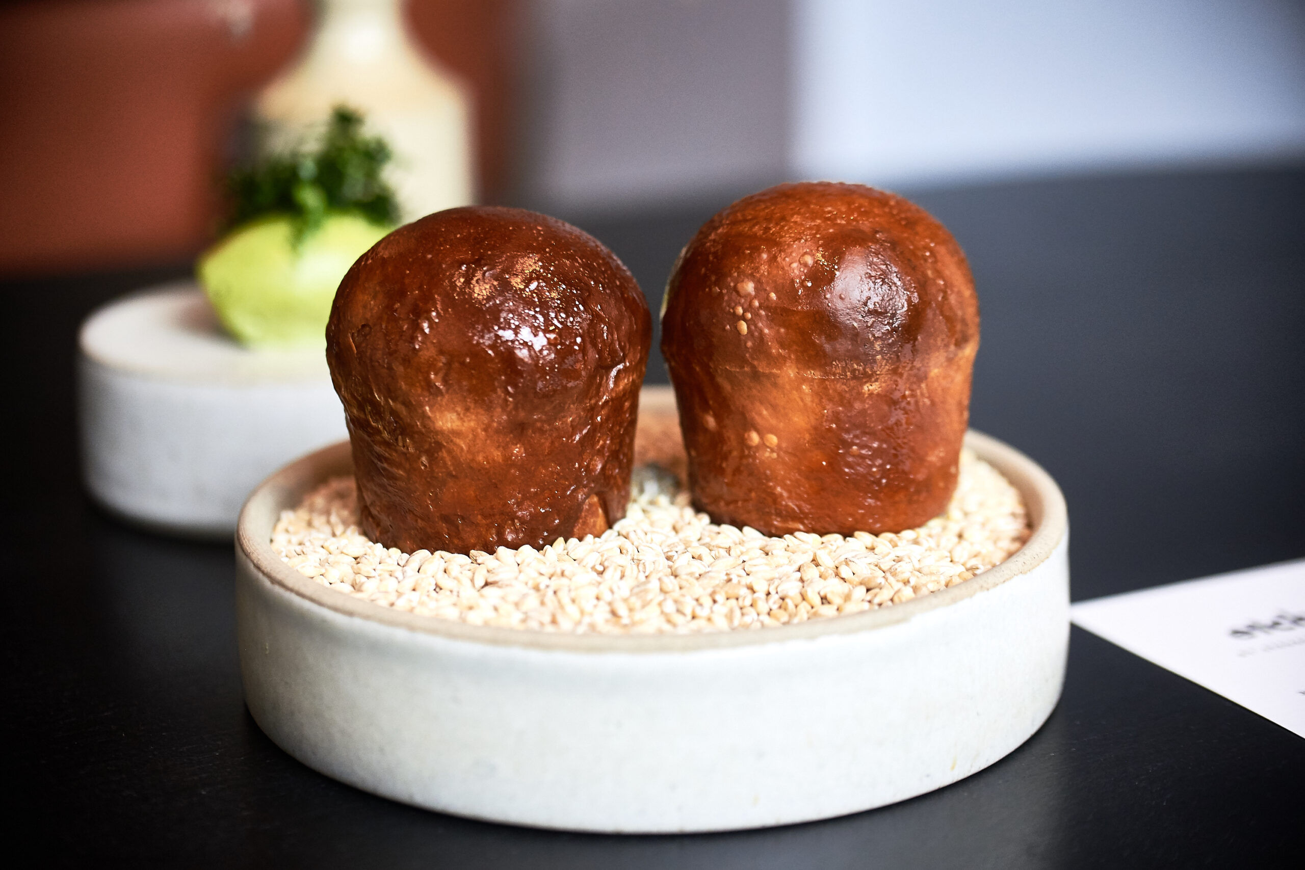 Brioche rolls served on a deep ceramic dish with a seaweed butter in the background at etch. restaurant.